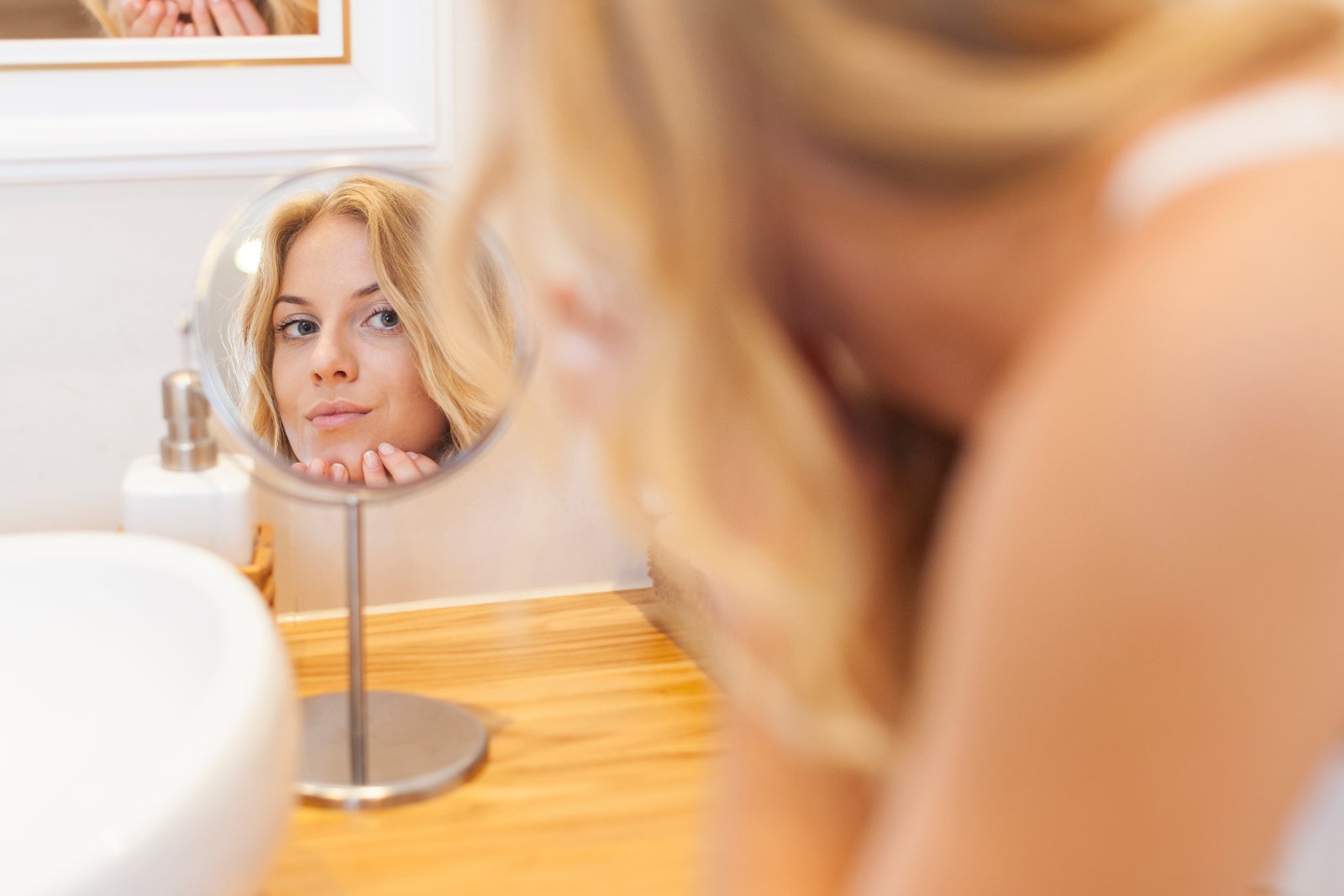 Vrouw verzorgt haar acnegevoelige huid voor de spiegel