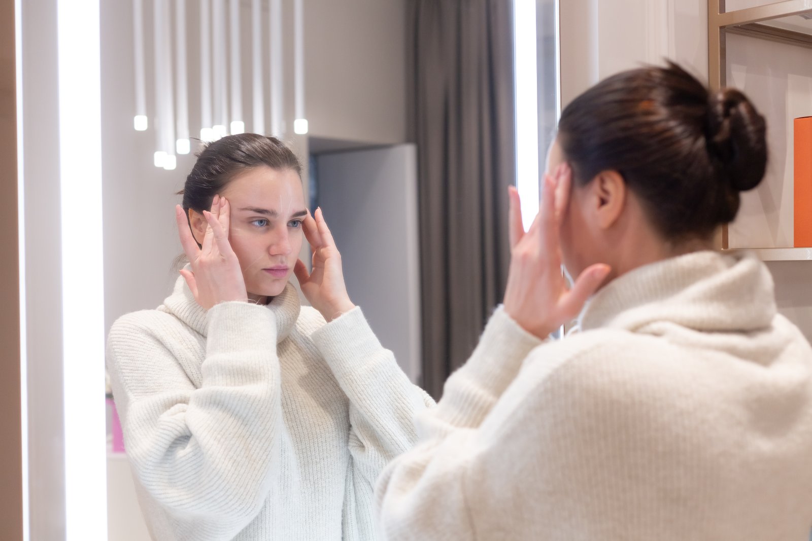 Jonge vrouw bekijkt haar huid in de spiegel - acne in cijfers
