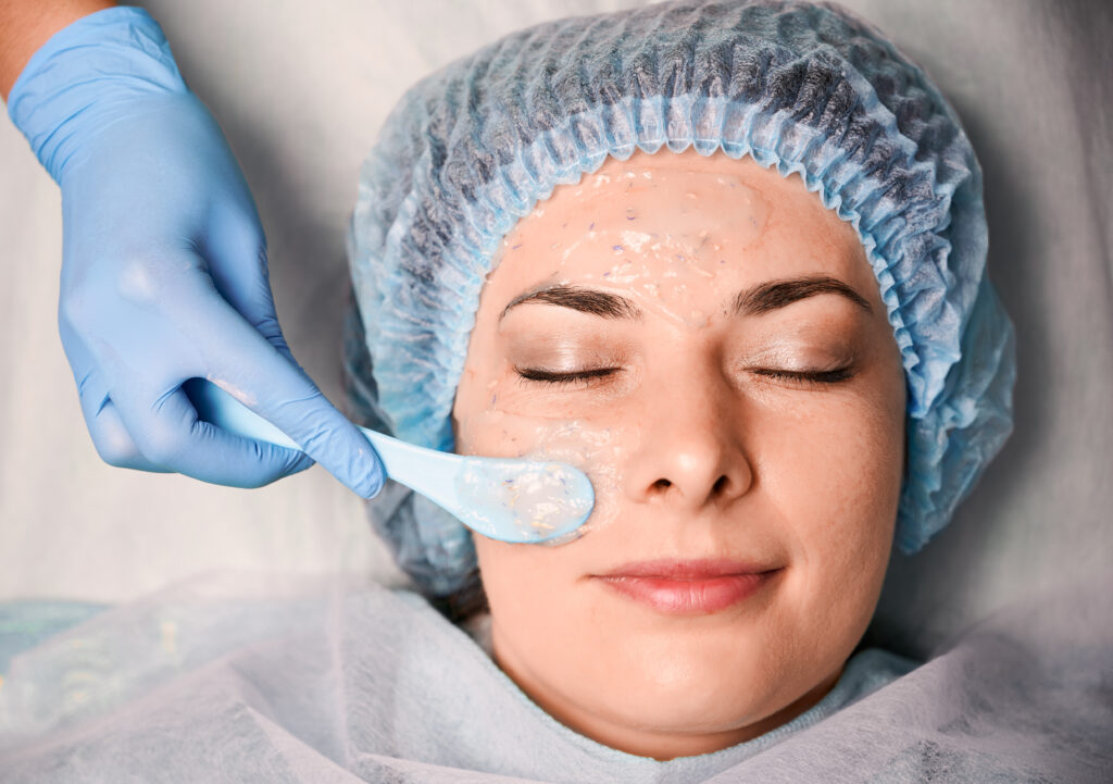 Huidtherapeut brengt een chemische peeling aan op het gezicht