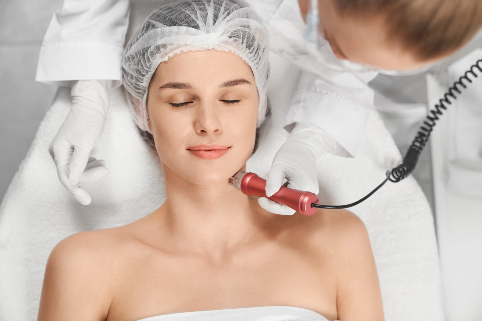 Lachende vrouw ondergaat hydrafacial behandeling op neus Vrouw geniet van hydrafacial behandeling — professionele huidverzorging voor cliënten uit Den Haag en omgeving